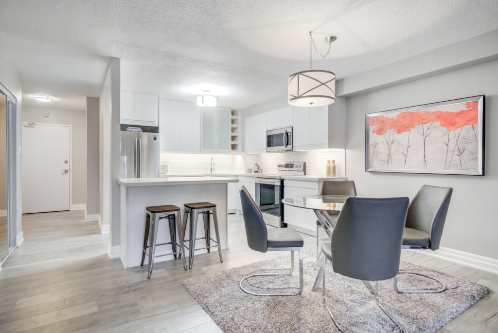 Interior image of a condominium showcasing a beautiful white kitchen with stainless steel appliances