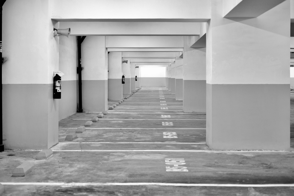 Black and white image of vacant parking stalls located underground.