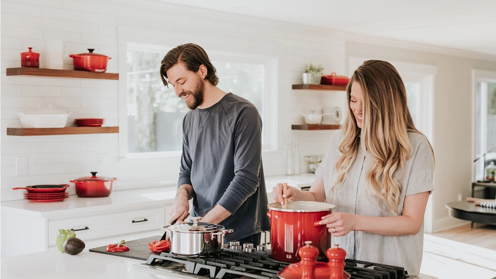 An image of young couple happily working in their kitchen of their dream rental property.