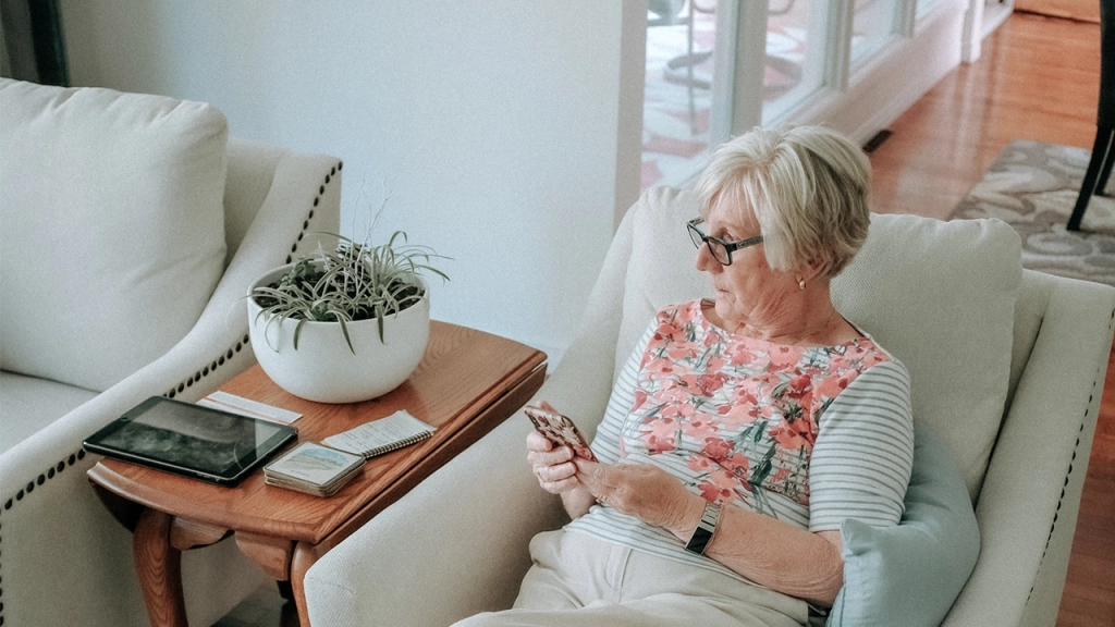 An older, mature lady sitting in her chair wondering if she should rent or own in retirement.