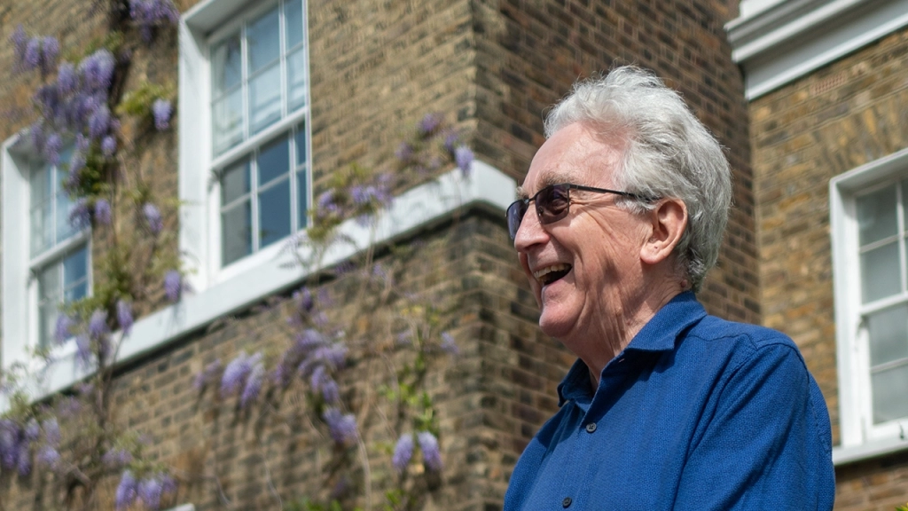 An older gentleman with a smile on his face happy for owning a home in retirement.