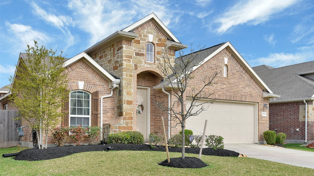 An image of a single-detached house, brick exterior, with a blue sky behind it. An image owned by someone who wondered, "Should I use a real estate agent to rent my house"