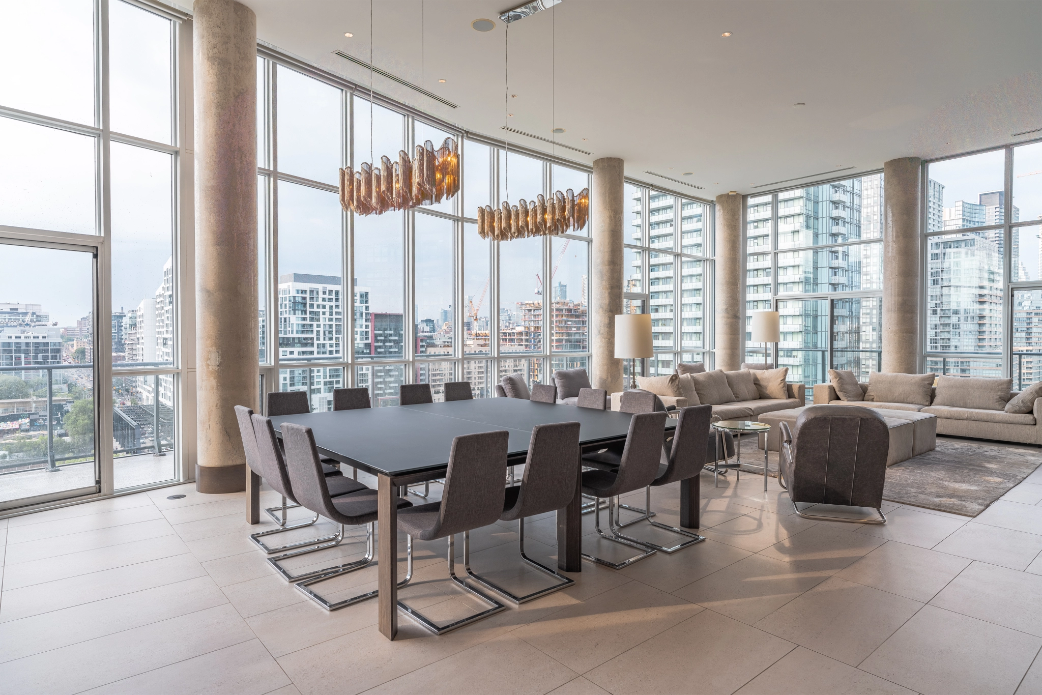 Interior image of 169 Fort York Blvd's upper penthouse showing the dining room table with the floor to ceiling windows open in the background facing north east.