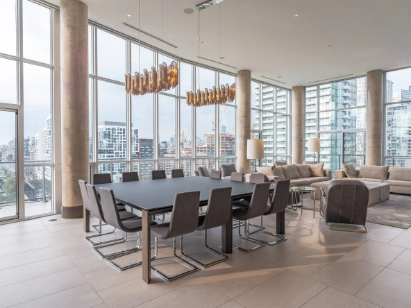 Interior image of 169 Fort York Blvd's upper penthouse showing the dining room table with the floor to ceiling windows open in the background facing north east.