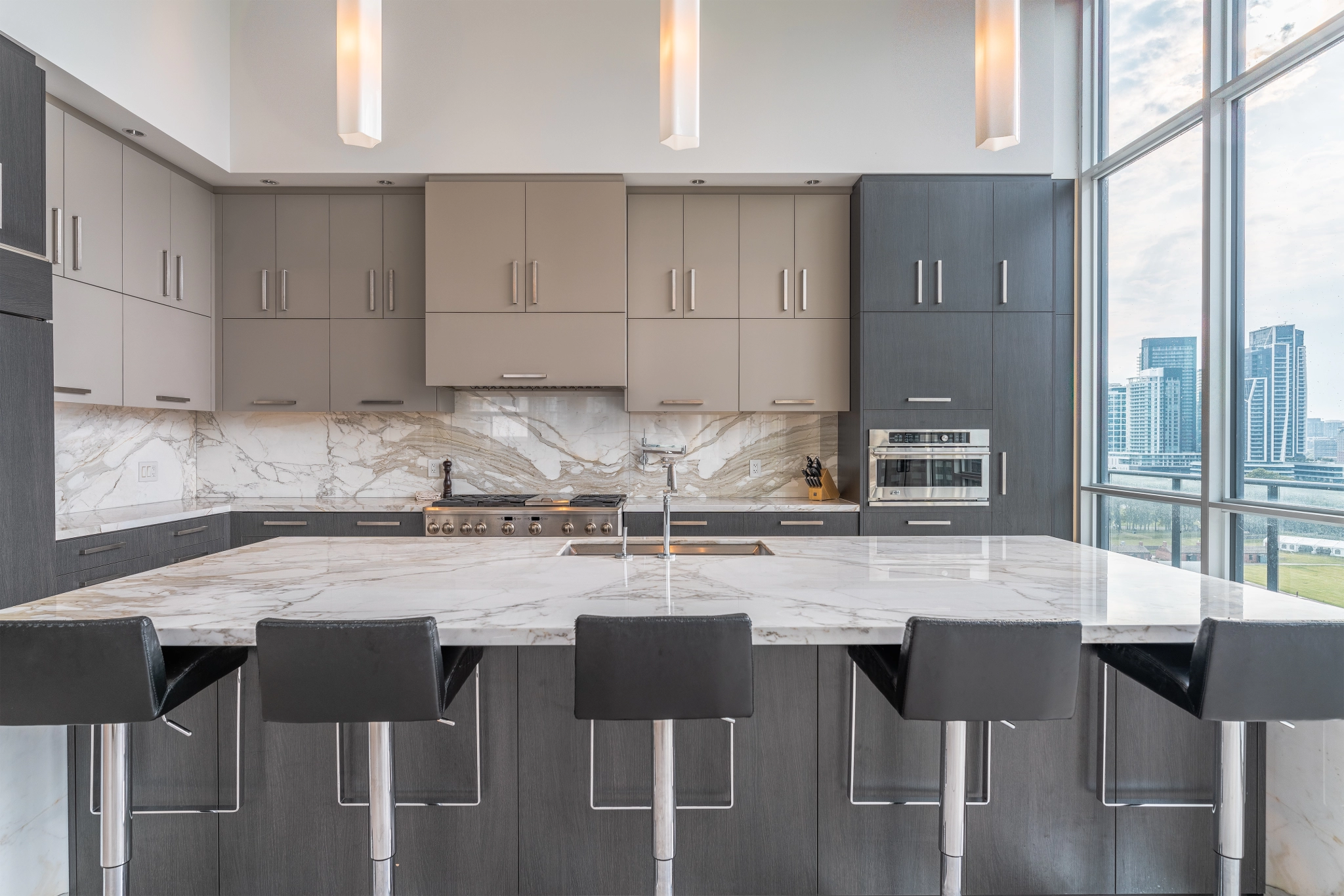 Interior image of 169 Fort York Blvd's upper penthouse showing kitchen island with the brown cabinetry in the back.