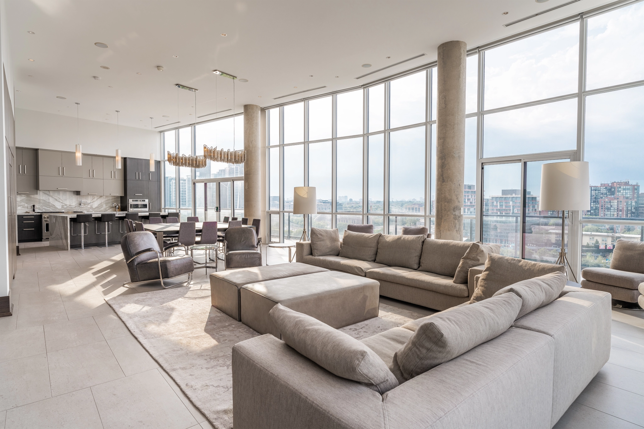 Interior image of 169 Fort York Blvd's upper penthouse showing the living room table with the floor to ceiling windows open in the background facing north west.