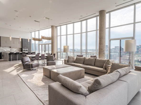 Interior image of 169 Fort York Blvd's upper penthouse showing the living room table with the floor to ceiling windows open in the background facing north west.