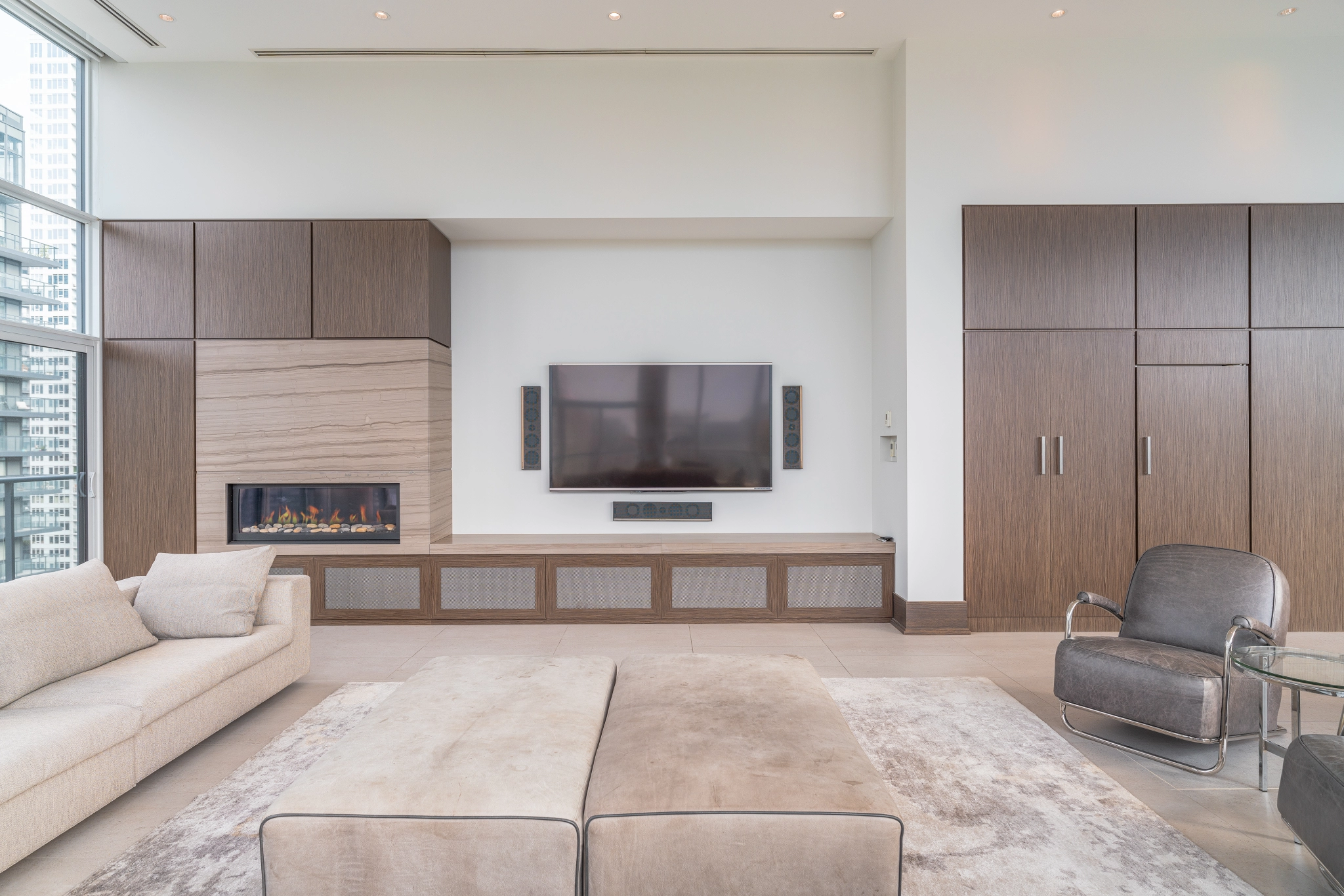 Interior image of 169 Fort York Blvd's upper penthouse showing living room facing the wall-mounted TV with a fireplace to the left.