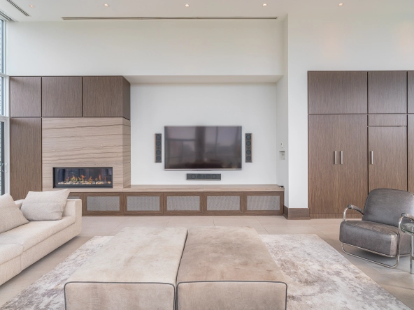 Interior image of 169 Fort York Blvd's upper penthouse showing living room facing the wall-mounted TV with a fireplace to the left.