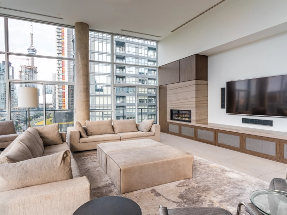 Interior image of 169 Fort York Blvd's upper penthouse showing the living room with the floor to ceiling windows open in the background with the CN tower in sight.