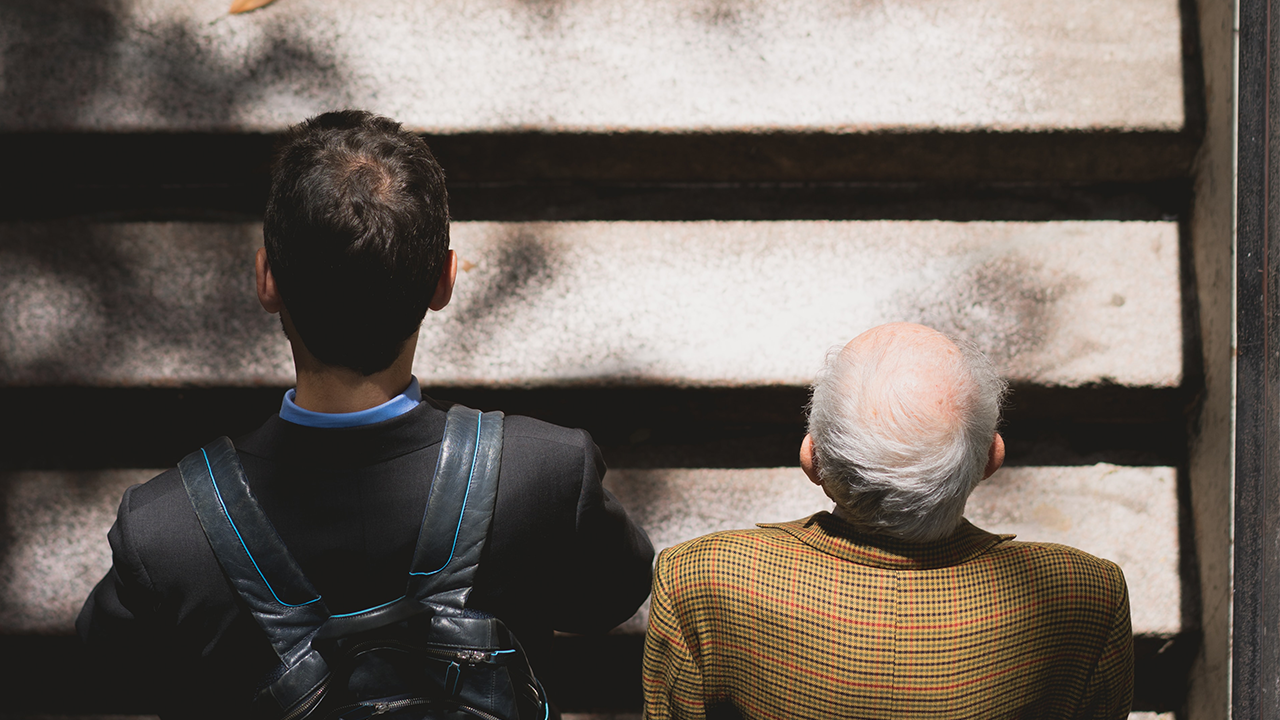 Image of the backs of an older and younger gentleman who are contemplating downsizing.