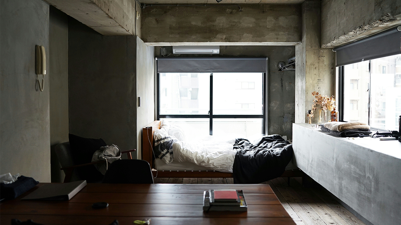 An image of a dark, loft-style, studio apartment. What is a studio apartment?