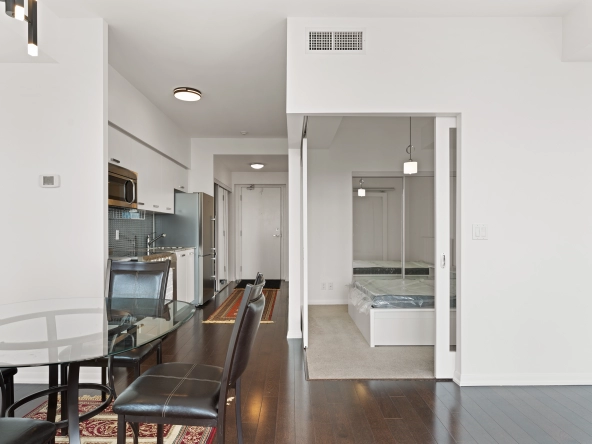 Living room looking towards the bedroom with doors opened at 832 Bay Street unit 4807 located in Toronto, Ontario, Canada.