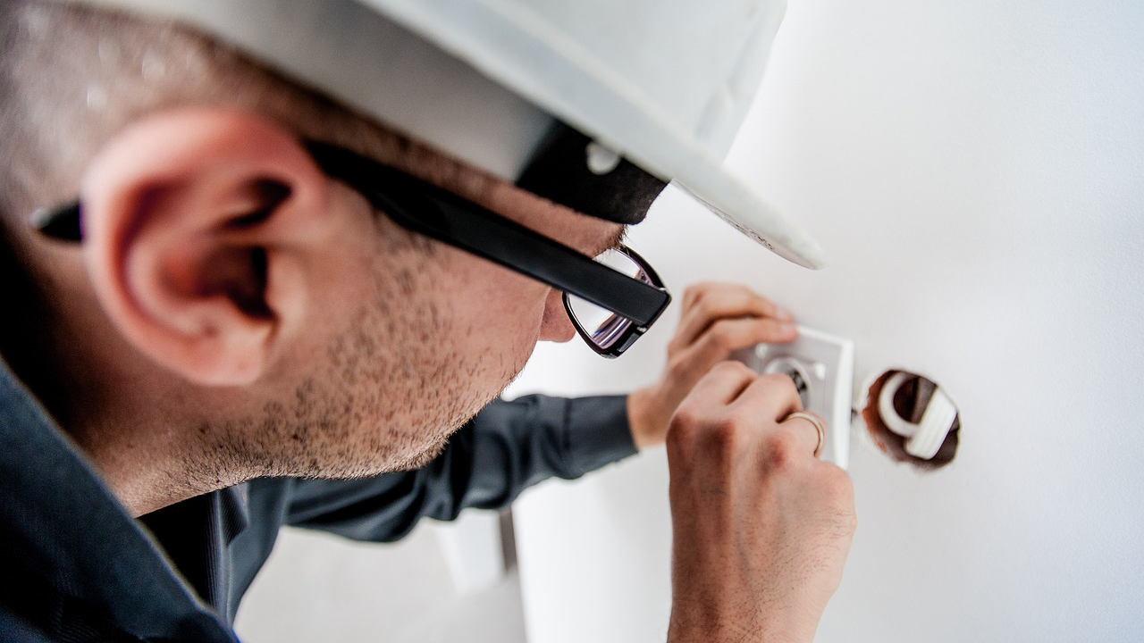 An image of a home inspector looking at an electrical outlet.
