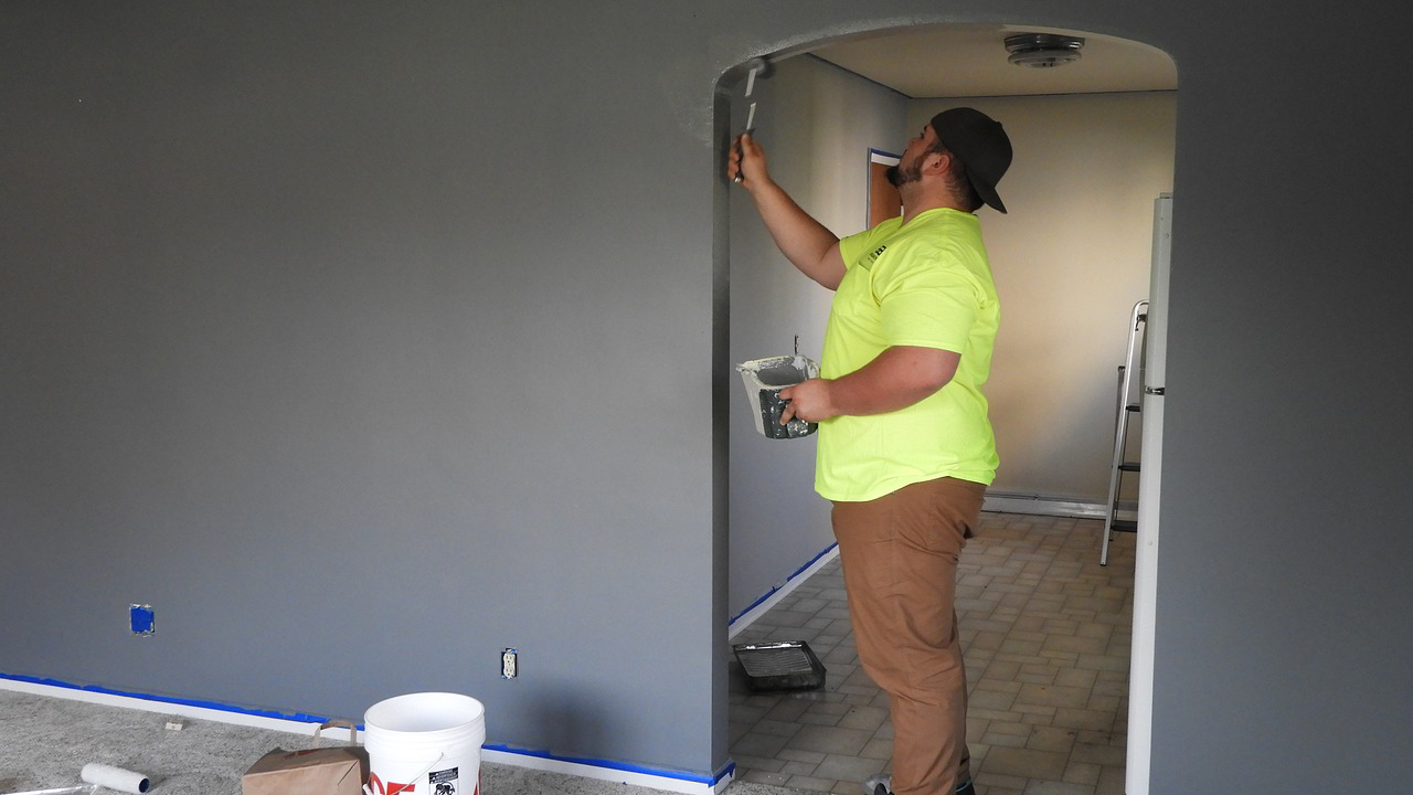 An image of a painter painting an archway of a home.